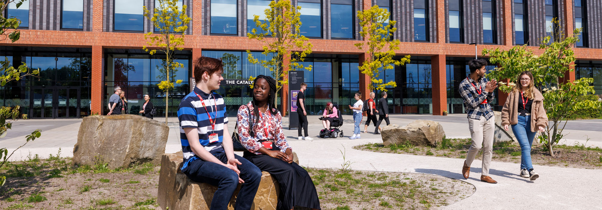 A diverse group of students wearing casual clothes socialising outside the front of the Catalyst building