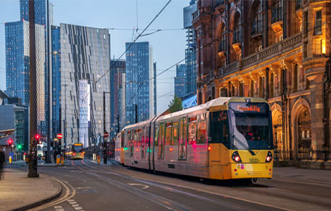 A tram in motion at Manchester city centre with city buildings in the background