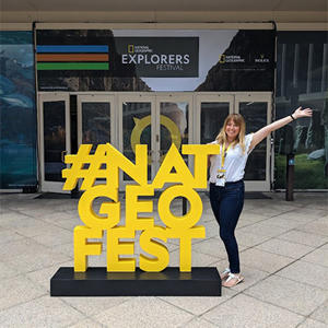 Claire Gwinnett photographed next to a yellow ' Nat Geo Fest' sign
