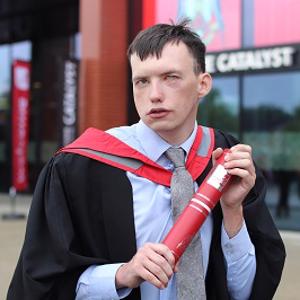 Jack Marshall in graduation robes holding a scroll