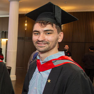 A male graduate in graduation cap and gown.