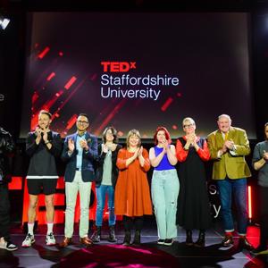 Peoplle lined up on stage in front of TEDxStaffordshireUniversity branding