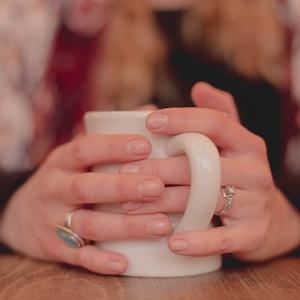 A woman's hands wrapped around a mug