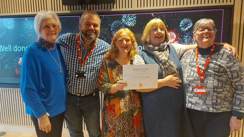 Five service users are attending an awards ceremony, holding an award and smiling for a photo