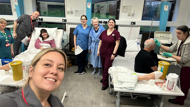 Service users and nurses are smiling for a group photo in the university ward environment