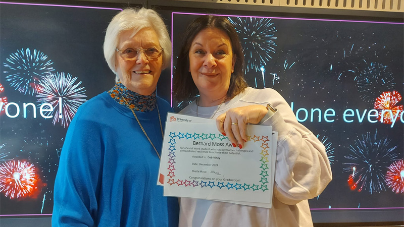 Two service users are attending an awards ceremony, holding an award and smiling for a photo