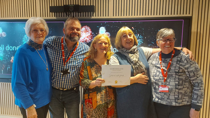 Five service users are attending an awards ceremony, holding an award and smiling for a photo