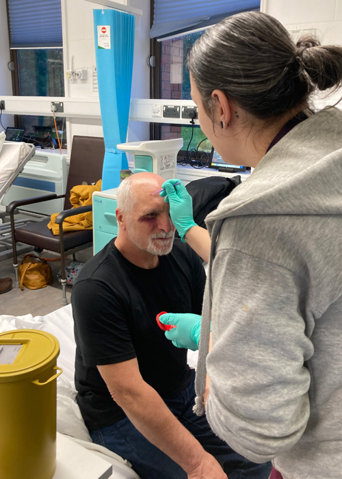 A man is receiving treatment on a head injury from a nurse in a medical simulation