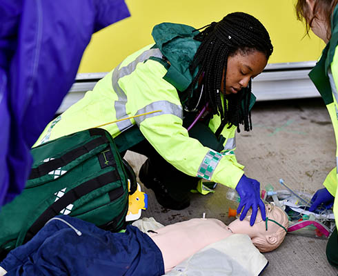 female paramedic is practicing skills using a dummy