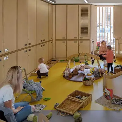 Children and adults are in the nursery room playing with toys
