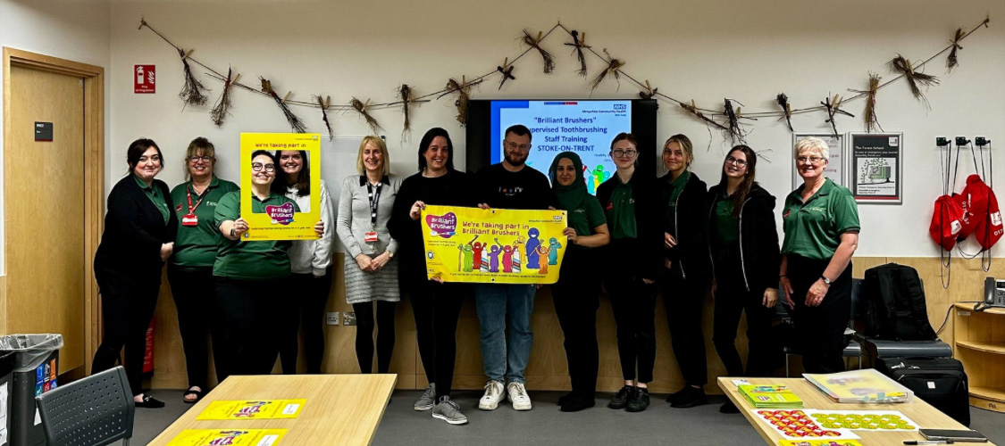 Nursery staff are all standing in a classroom for a group photograph
