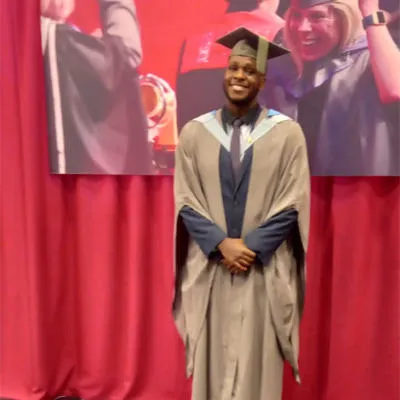 Banji wearing a grey graduation cap and gown