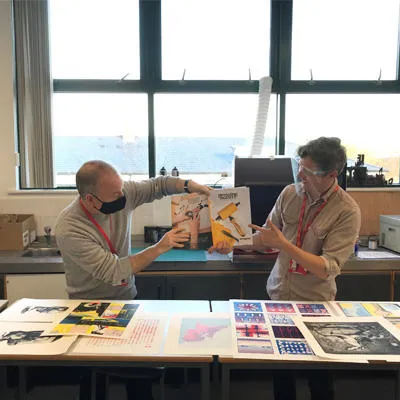 Ed and Joel in the print office space holding up modern designs