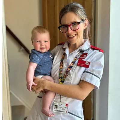 Kayleigh is wearing a white nurse uniform holding a baby
