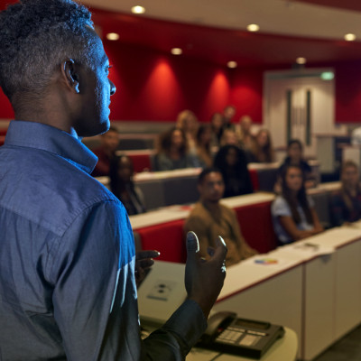 A visiting speaker presenting to a filled lecture theatre