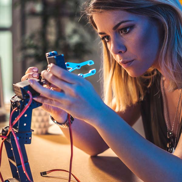 young female graduate working on robotic arm