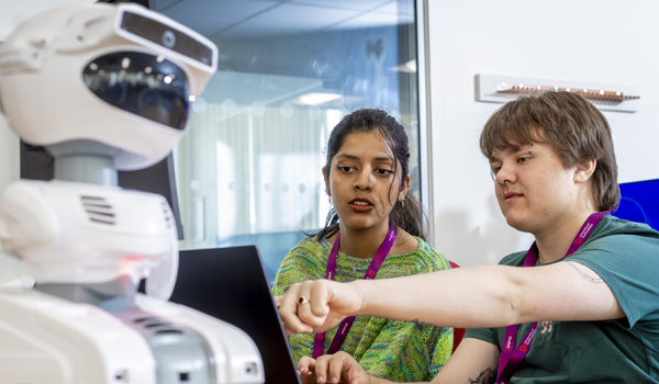 Two young students are collaborating together on programming a robot