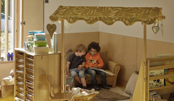 Two young boys are sitting together reading a book in the nursery