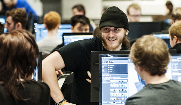 A group of male students are sitting in the PC lab chatting and working