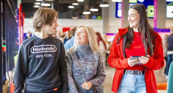 A parent, child, and student ambassador are walking and chatting together during an open day