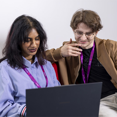 A female and male student are sitting relaxed, working together on a laptop