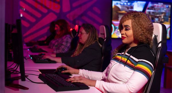 Female students wearing casual clothing using gaming computers in the ambient-lit esports hub