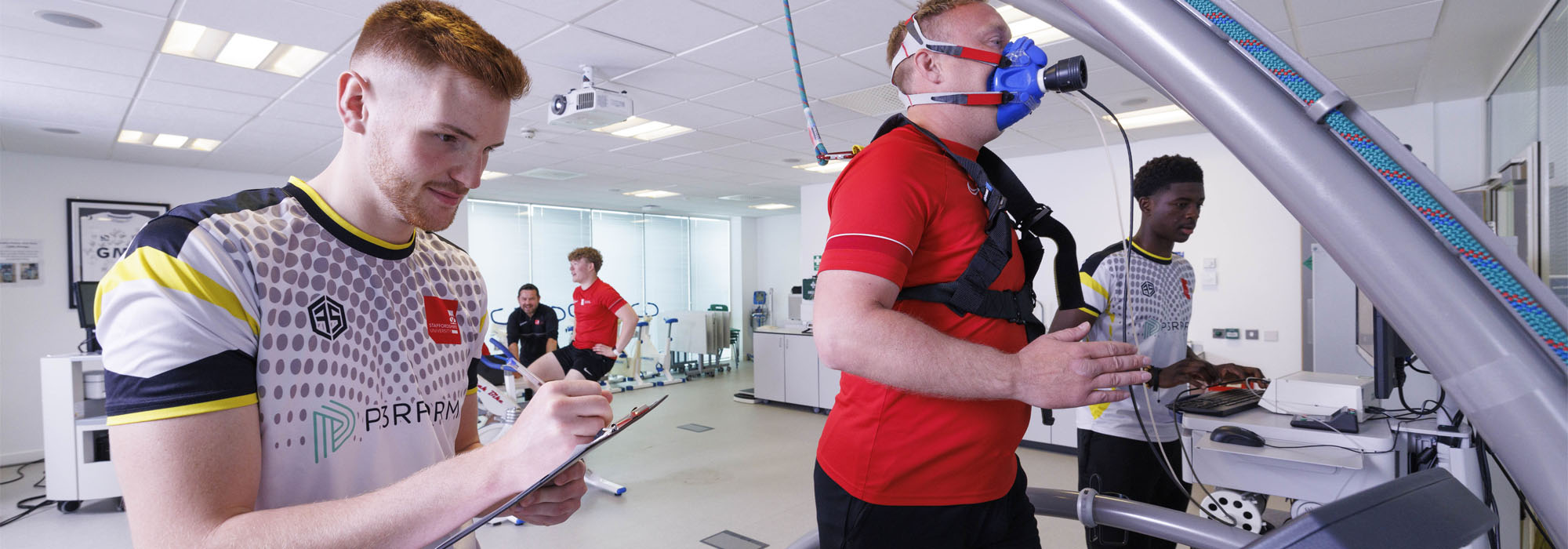 A group of male students wearing sports clothing using the running machine alongside various physiological monitoring equipment in the sports and exercise lab