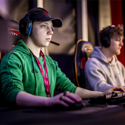 Gaming students wearing headsets are using the gaming PCs in the arena