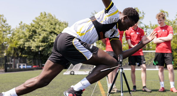 A sports student wearing football kit is running on the field