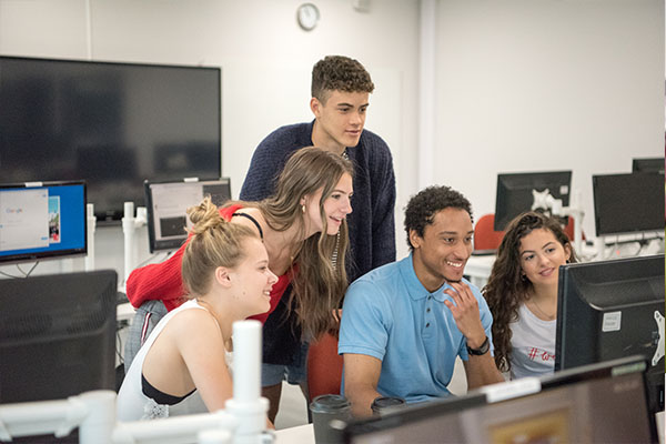 Group of students collaborating on work around a PC