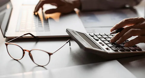 person using calculator and laptop on a desk