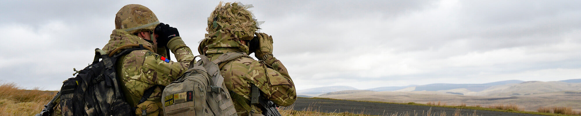 Two members of HM forces looking through binoculars