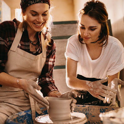 Two females throwing a pot in a pottery making studio