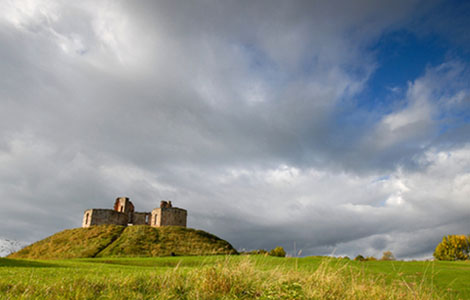 Scenic view of Stafford Castle surrounded by grass on a cloudy day