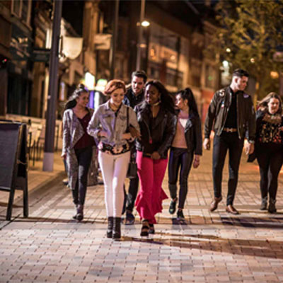 A group of male and female students walking and talking in the Cultural Quarter in Hanley in the evening