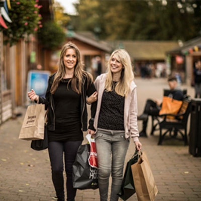 Two females walking together holding shopping bags at Trentham retail village