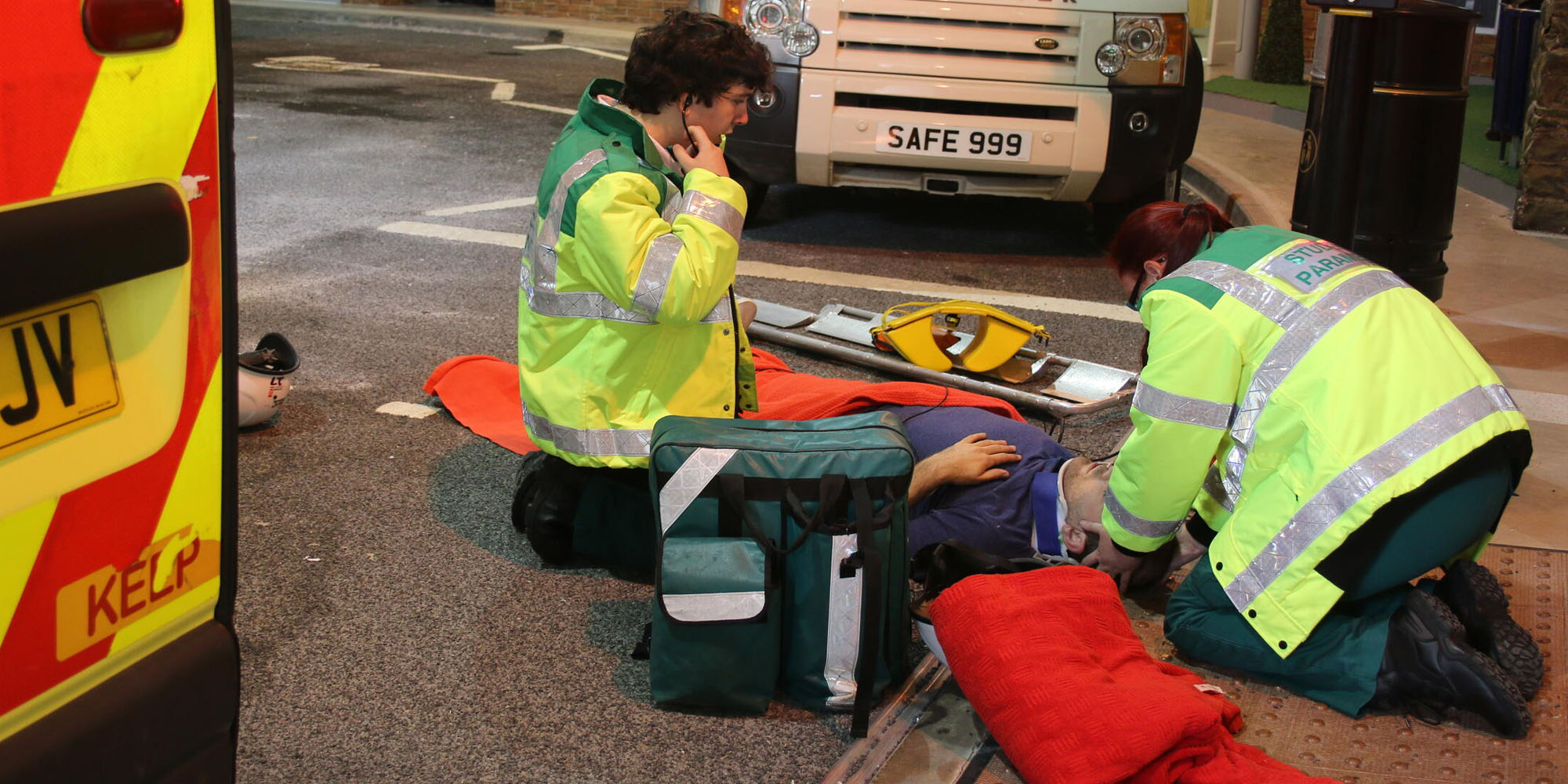 Two student paramedics attending to a patient lying on the floor in a simulation street setting