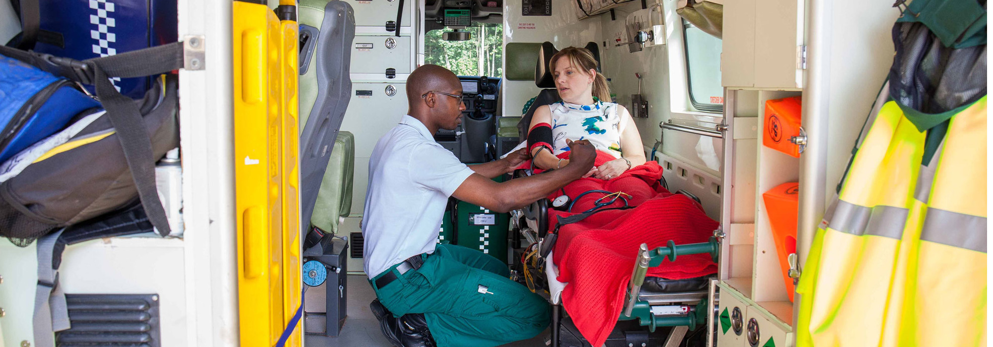A paramedic student is testing blood pressure of a patient in a van