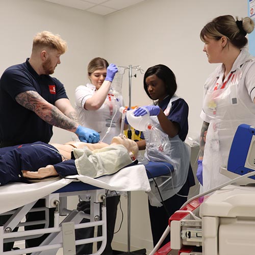 Nursing and allied health students practicing their skills on a simulation medical dummy.