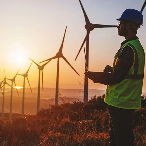 Person standing next to a line of wind turbines.