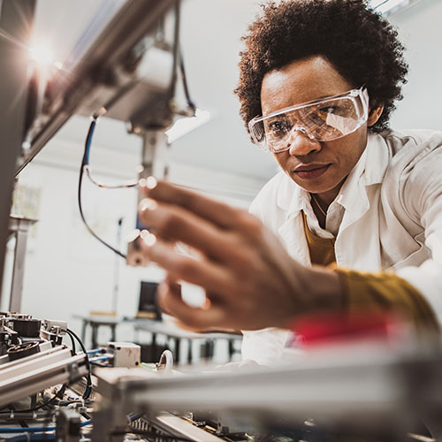 Black female researcher wearing safety goggles using machinery in the lab