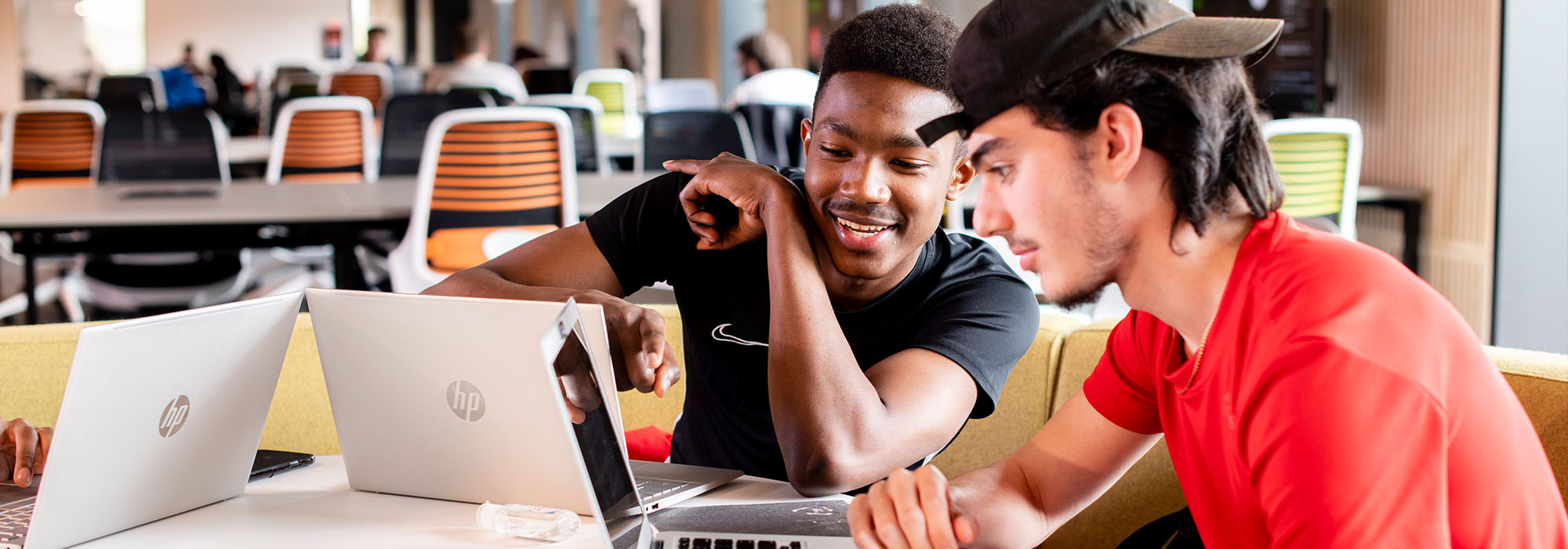 Two male students working together on laptops in our catalyst building
