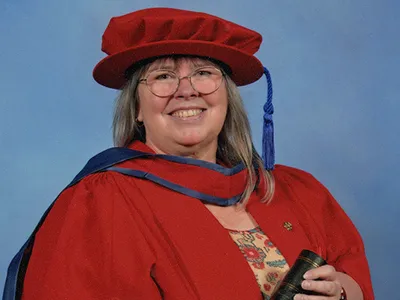 Smiling woman in a red graduation gown