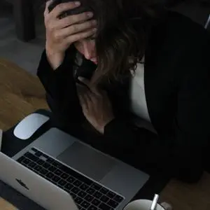 A woman sat a computer looking stressed