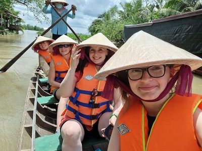 Students wearing traditional Vietnamese hats aboard a boat