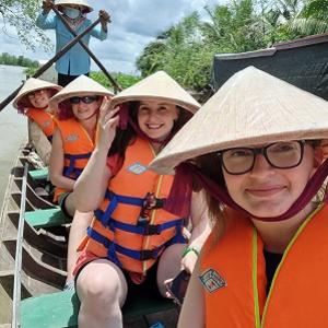 Students wearing traditional Vietnamese hats aboard a boat