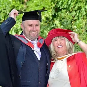 Man and woman in graduation dress outdoors
