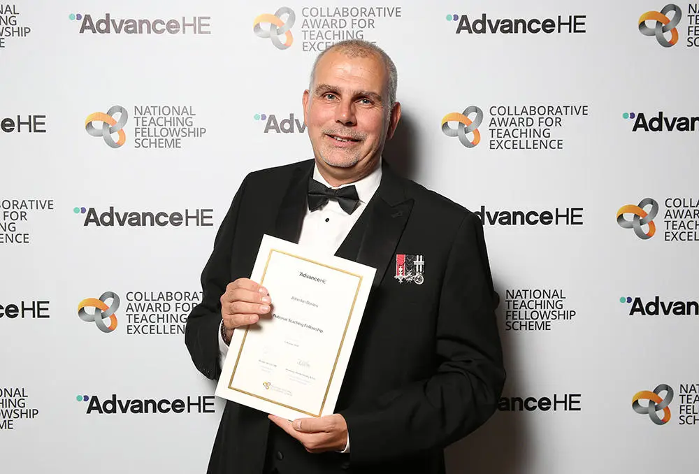 Ian Davies in a tuxedo holding a certificate