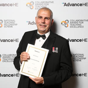 Ian Davies in a tuxedo holding a certificate