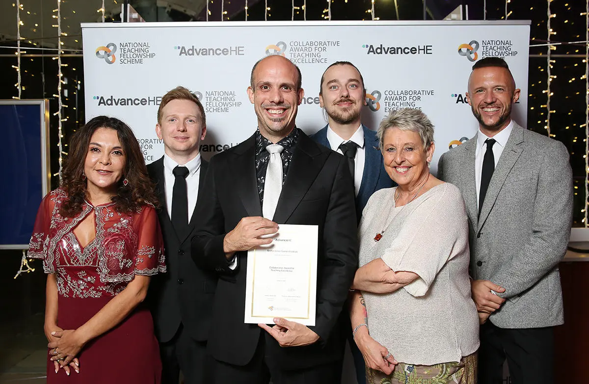 A group of six people smiling with the central figures holding a certificate